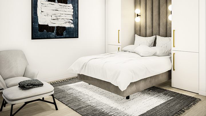 Contemporary bedroom with grey bed and white wardrobes with gold handles